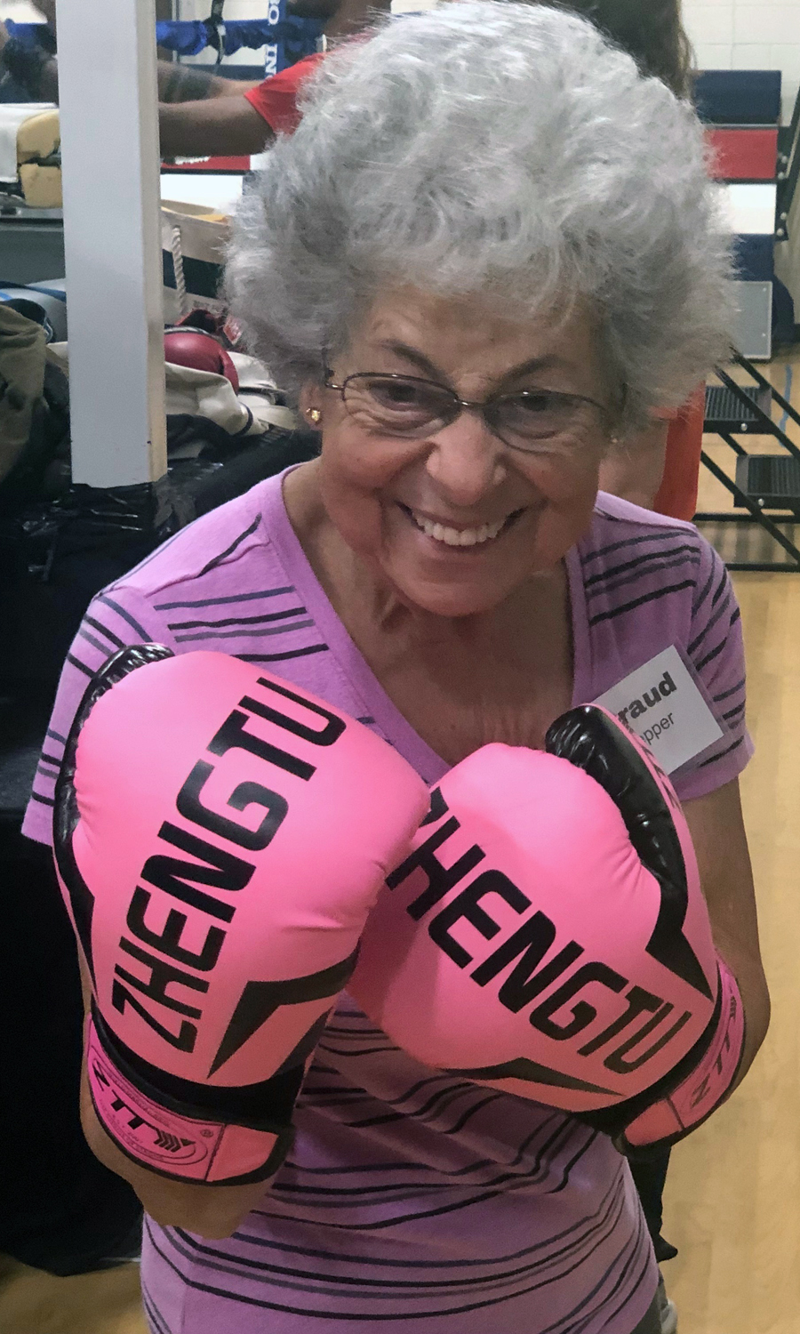 older woman wearing pink boxing gloves