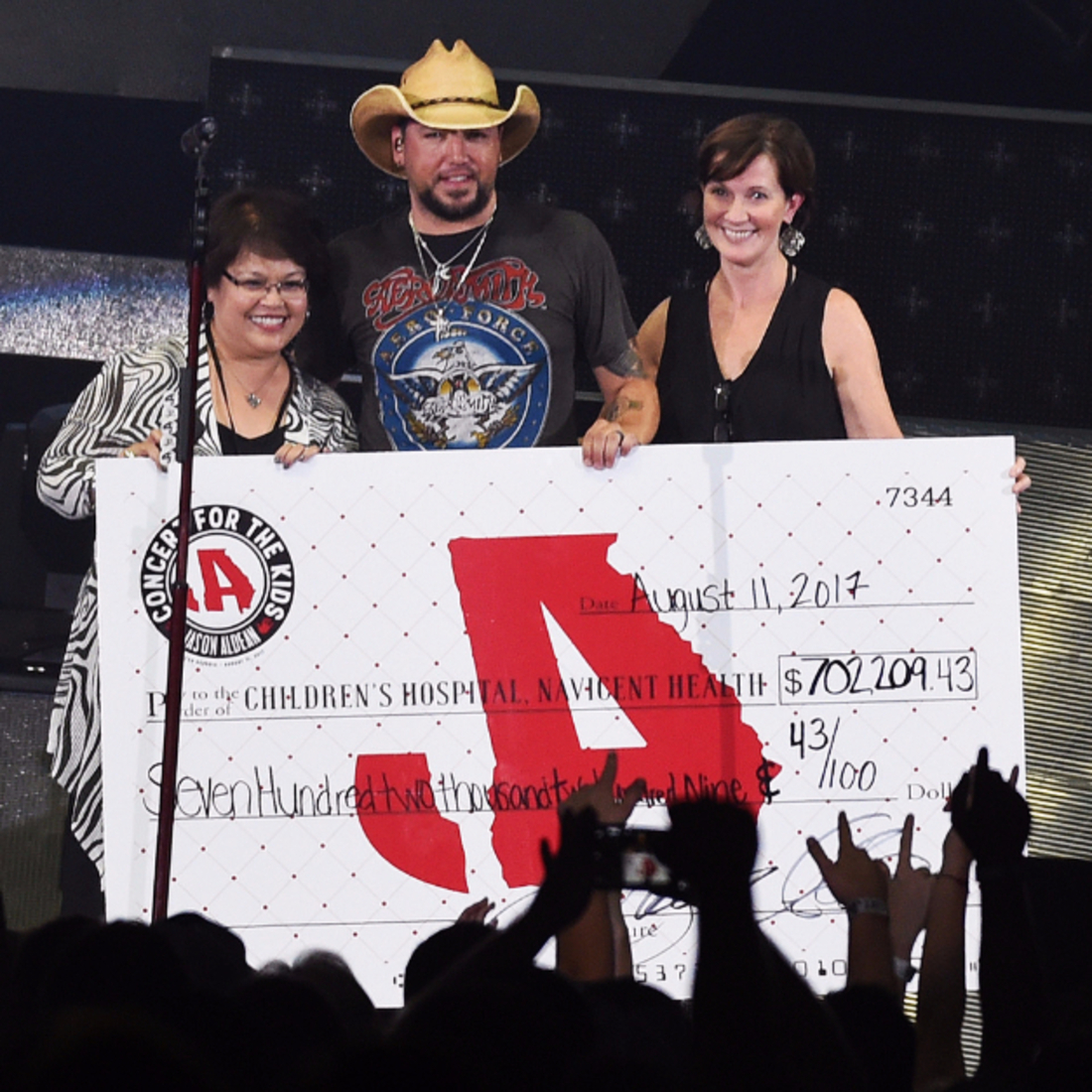 Jason Aldean standing with $700k charity check