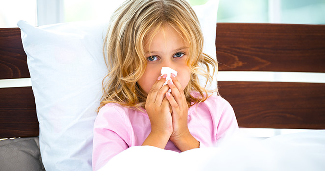 Small girl in bed holding a tissue against her nose