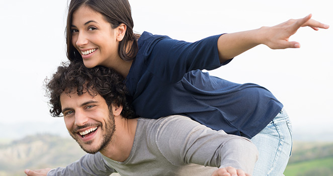 Woman getting a piggy-bck-ride with her boyfriend and being silly