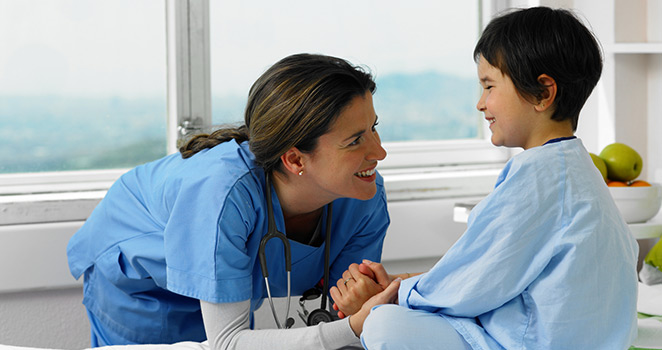 Nurse smiling at a young boy on the exam table