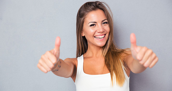 Young woman standing with her thumbs up and smiling