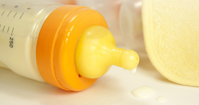 Baby bottle with a drop of formula dripping from the nipple