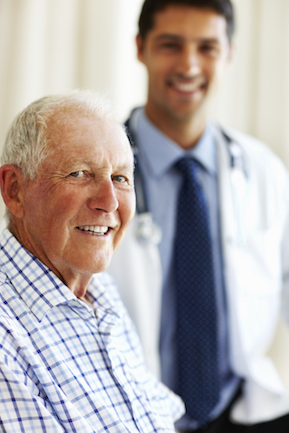 Elderly patient in the fore-ground smiling with the doctor in the background