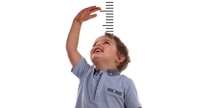 Small boy standing in front of a height ruler