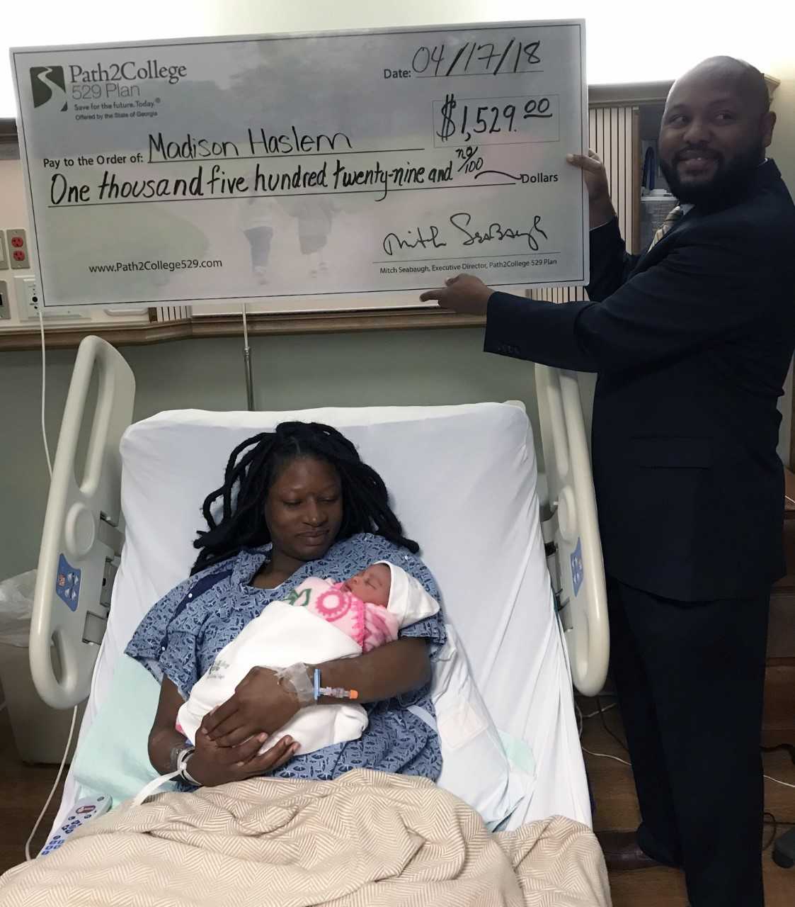 Family of first tax day baby poses with Path2College donation check
