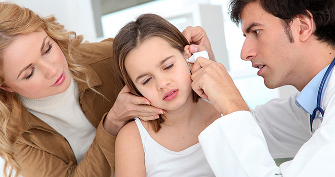 Doctor looking into a young girl's ear