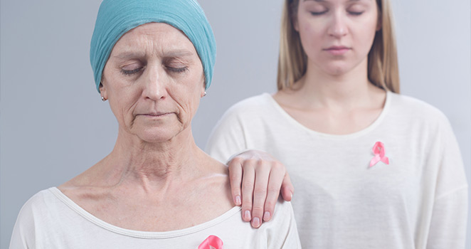 Young woman prays with an older woman who has cancer