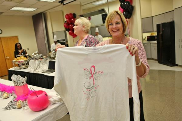 Lady holding up a tee shirt designed with the fundraiser logo