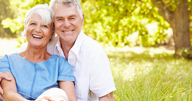 Older couple sitting in the grass smiling