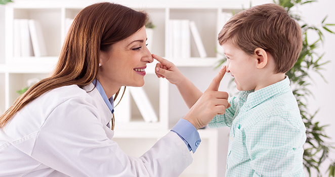 Doctor and little boy touching eachother on the nose and smiling