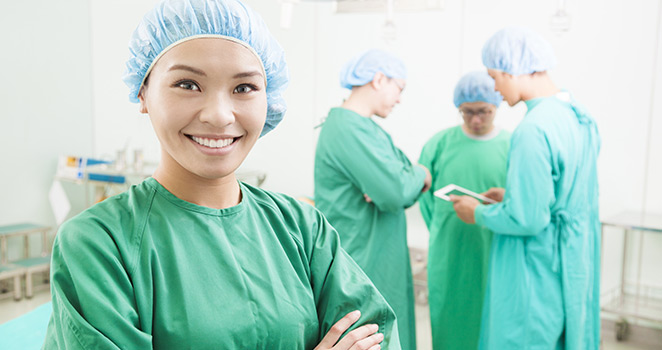 Young doctor smiling and standing in a room with other doctors in the background