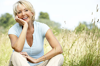 Middle aged woman sitting inthe grass and smiling