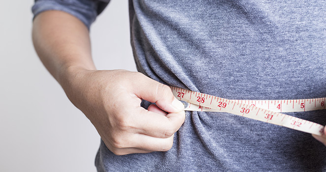 Person measuring their trim waist line